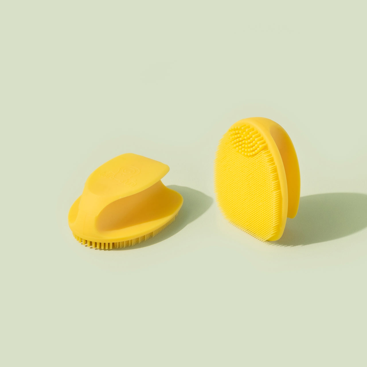 Two Tubby Todd brushes, one laid face-down and the other facing up on a light green background.